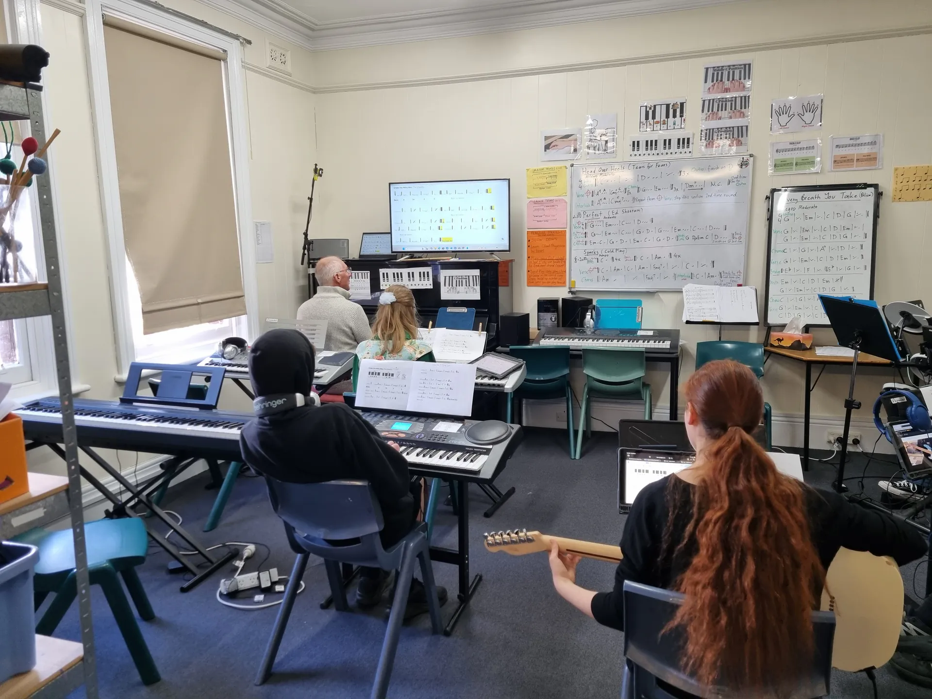 Students playing keyboards and guitars in music class